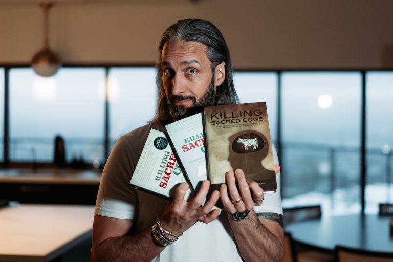 Garrett Gunderson holding three editions of Killing Sacred Cows
