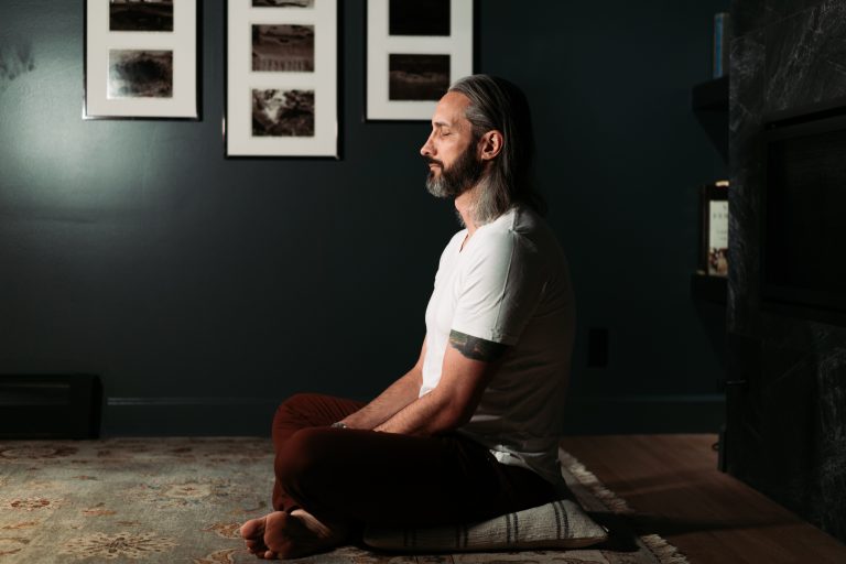 Garrett Gunderson meditating in a dark room, reflecting on intentional money habits and millionaire budgeting.