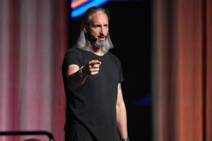 Garrett Gunderson speaking on stage and pointing toward the audience